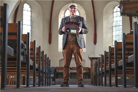 Der Leeraner Pastor Ingo Brookmann zeigt den neuen „digitalen Klingelbeutel“: In Loga muss niemand mehr Münzen in ein Säckchen werfen. Hintergrund: Die Bank verlangt seit einiger Zeit eine Gebühr für die Einzahlung von Münzgeld – das gilt auch für die Kollekte.