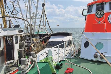 Der Seenotrettungskreuzer „Hermann Rudolf Meyer“ liegt längsseits am havarierten Motorboot, das zuvor von mehreren Fischkuttern vor dem Kentern gerettet worden war.