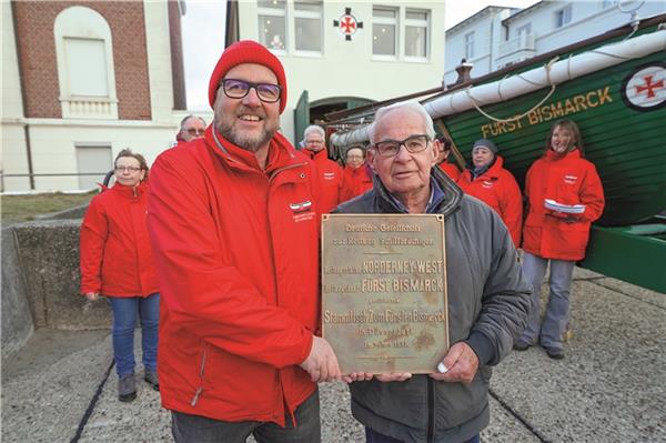 Frank Kahl, ehrenamtlicher Mitarbeiter, und Eilt Wessels, Mitglied des beschlussfassenden Gremiums der DGzRS, freuen sich über die Rückkehr des Schildes in den historischen Rettungsschuppen.