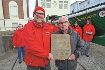 Frank Kahl, ehrenamtlicher Mitarbeiter, und Eilt Wessels, Mitglied des beschlussfassenden Gremiums der DGzRS, freuen sich über die Rückkehr des Schildes in den historischen Rettungsschuppen.